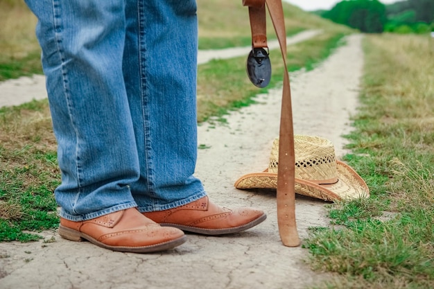 Pernas de cowboy em sapatos no parque no fundo da natureza O homem no rancho