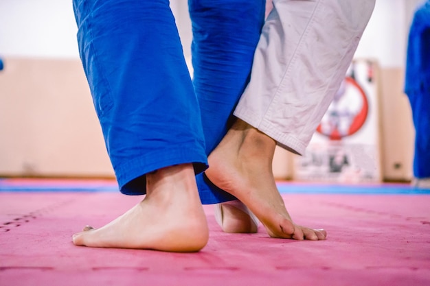 Pernas de dois jovens estagiários de jiujitsu em combate descalço em um tatame