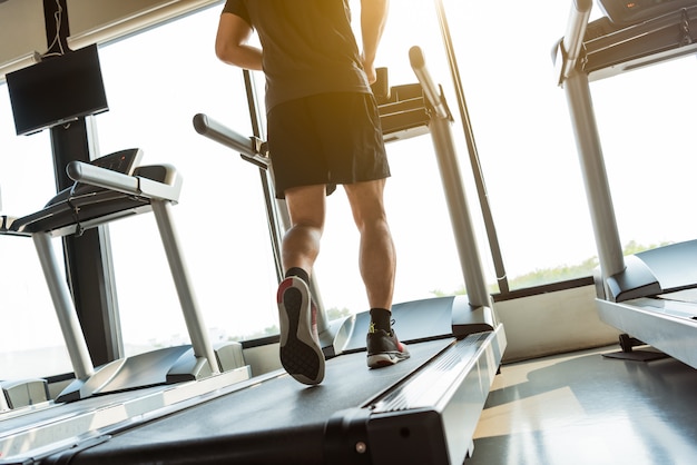 Pernas de esportista correndo na esteira no centro de fitness ginásio. esporte e conceito de estilo de vida saudável.