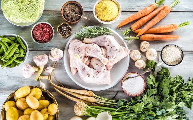 Pernas de frango cru com especiarias e vegetais variados.