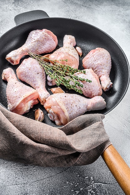 Pernas de frango cru cru com especiarias e alho, pronto para cozinhar em uma panela