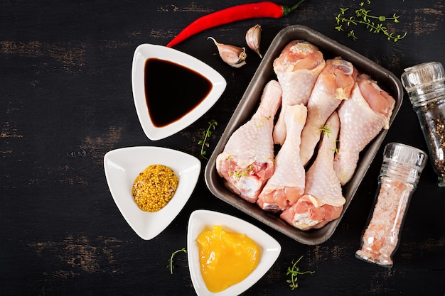 Pernas de frango cru cru e especiarias na mesa escura