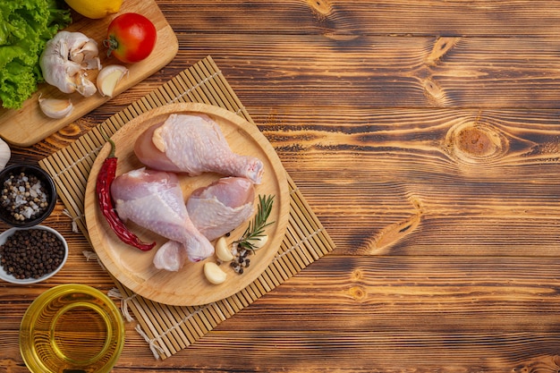 Pernas de frango cru cru na superfície de madeira escura.