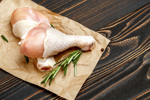 Pernas de frango cru em assadeira em uma mesa de madeira