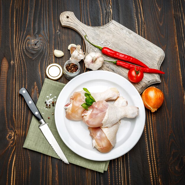 Pernas de frango cru em assadeira em uma mesa de madeira