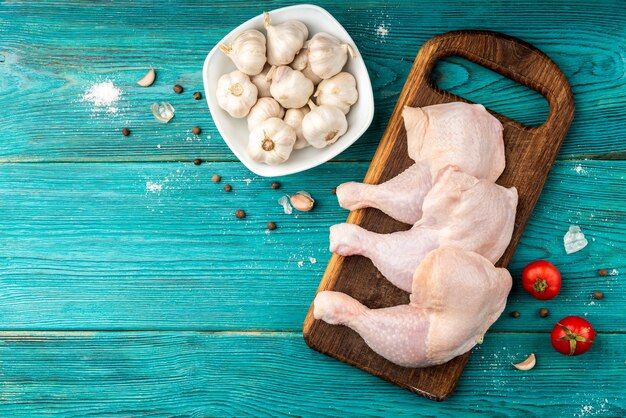 Pernas de frango cru em superfície de madeira azul