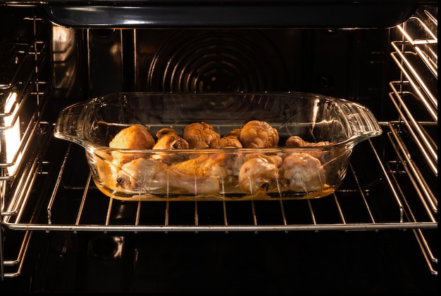 Pernas de frango em uma bandeja de vidro são assadas no forno