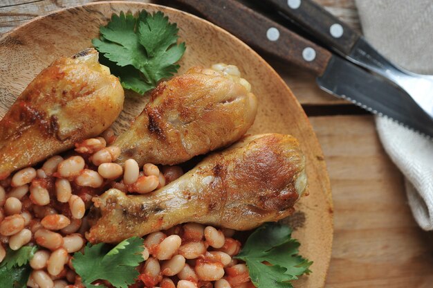 Pernas de frango frito com feijão e tomate em uma placa de madeira