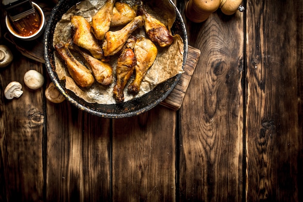 Pernas de frango frito com molho de tomate. Em uma mesa de madeira.