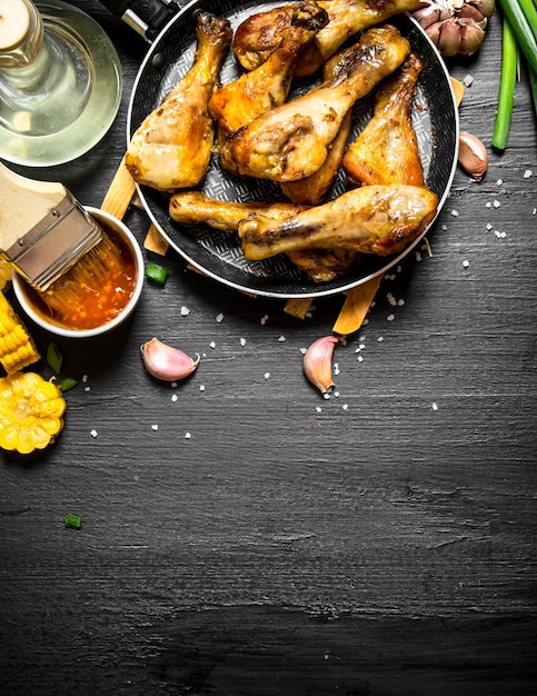 Pernas de frango frito com pedaços de milho e molho.