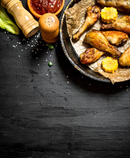 Pernas de frango frito com pedaços de milho e molho.