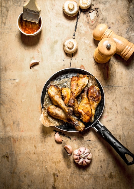 Pernas de frango frito em uma panela com molho de tomate, cogumelos e alho.