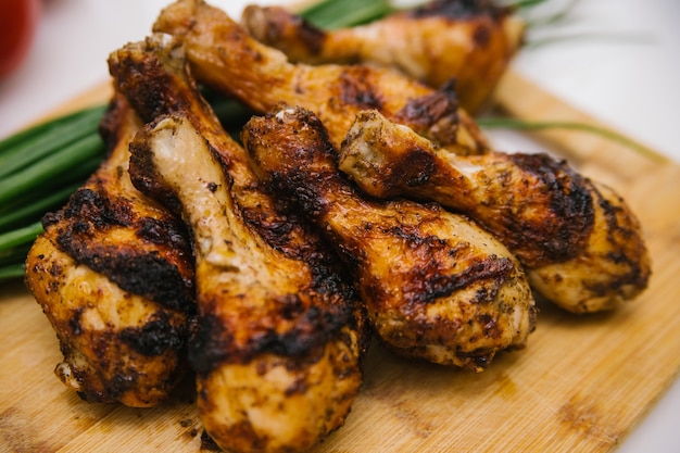 pernas de frango frito mentem sobre uma placa de madeira. kebab de frango com molho de legumes.