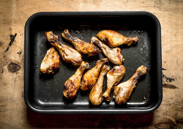 Pernas de frango na assadeira sobre uma mesa de madeira