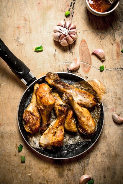 Pernas de frango picantes com alho e molho de tomate. Em uma mesa de madeira.