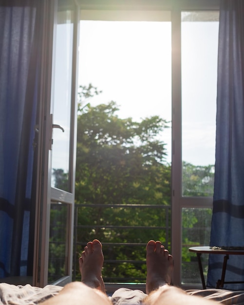 Pernas de homem deitado na cama Ver na janela