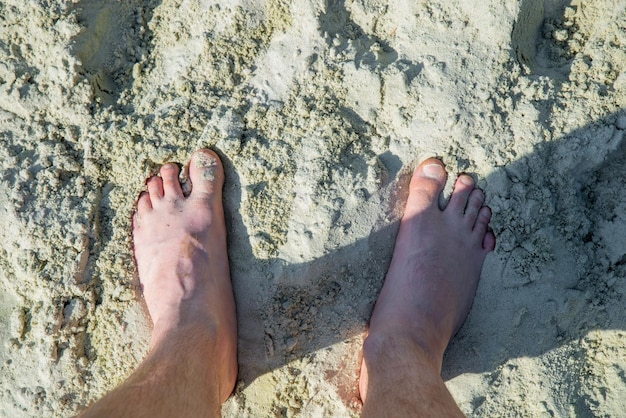 Pernas de homem na areia vista aérea horário de verão