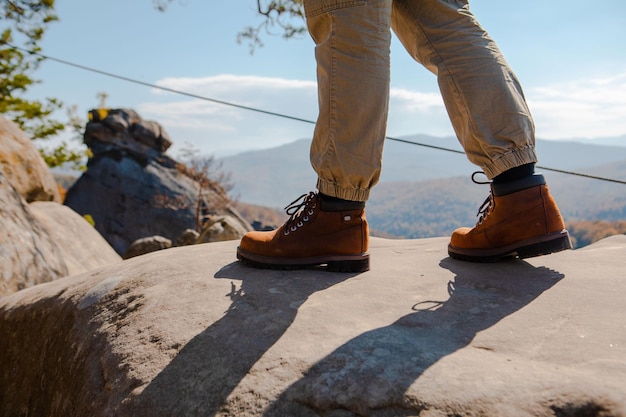 Pernas de homens de conceito de caminhada em botas na rocha