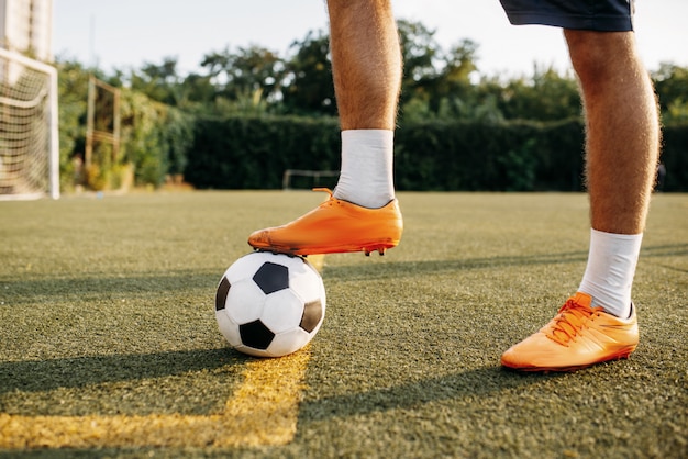 Pernas de jogador de futebol masculino com bola em pé on-line no campo. jogador de futebol no estádio ao ar livre, treino antes da partida de futebol