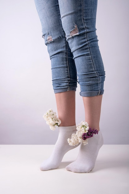 Pernas de menina em meias nas quais as flores lilás são inseridas conceito de veias e pernas de saúde feminina