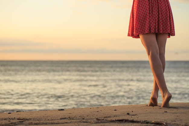 Foto pernas de mulher bonita, caminhando na praia.