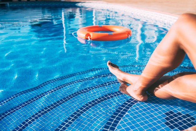 Pernas de mulher em uma piscina com salva-vidas