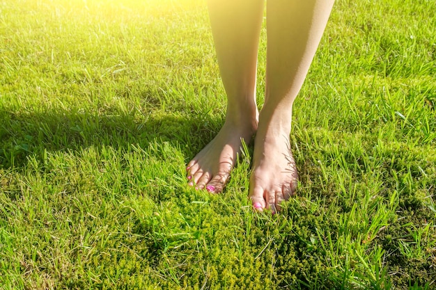 Pernas de mulher na grama verde andar descalço na grama verde fresca