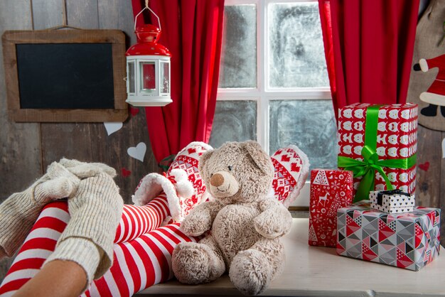 Pernas de mulher Santa com urso de pelúcia, cena de Natal