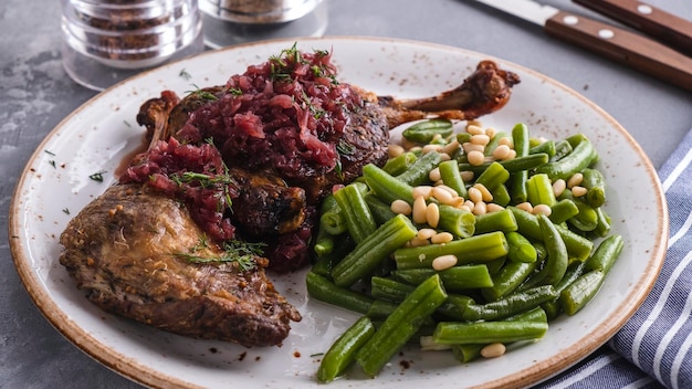 Pernas de pato assado suculento com feijão verde e pinhões em um prato servido com garfo e faca Comida de restaurante