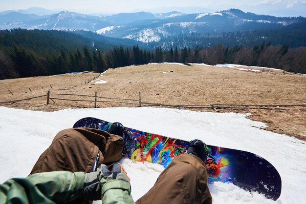 Pernas de snowboarder e snowboard azul brilhante na neve branca linda paisagem de inverno