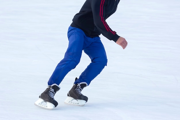 Pernas de um homem patinando em uma pista de gelo. Hobbies e esportes. Férias e atividades de inverno.