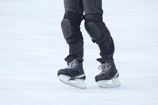 Pernas de um homem patinando em uma pista de gelo. Hobbies e esportes. Férias e atividades de inverno.