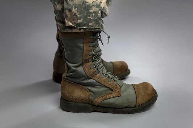 Foto pernas de um soldado camuflado e botas do exército em um fundo cinza conflitos e crises militares closeup