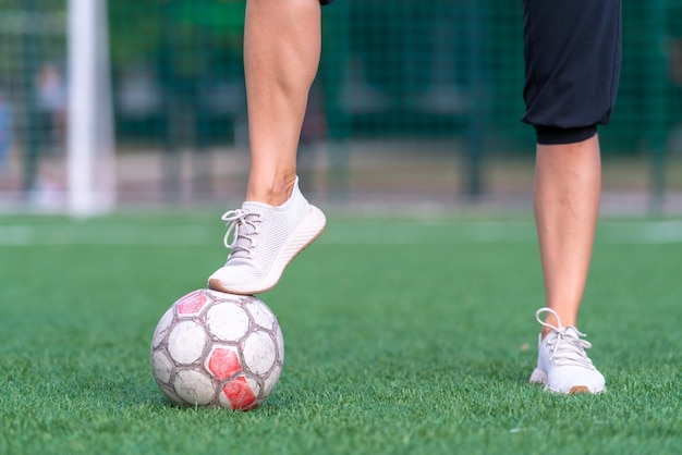 Pernas de uma jovem musculosa com pé sobre uma bola