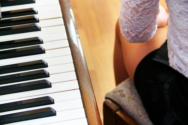 Pernas de uma jovem pianista ao lado de um piano teclas de piano e pernas de uma pianista instrumento musical de teclado conceito de música