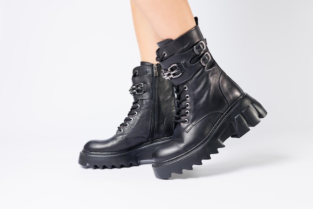 Pernas de uma mulher em botas de couro preto de uma nova coleção em um fundo branco pernas de uma garota em botas de couro na moda primavera 2022