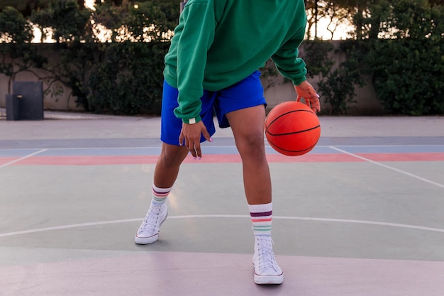 Pernas de uma mulher latina irreconhecível jogando em uma quadra de basquete em um conceito de parque urbano de esporte urbano no espaço de cópia de rua para texto