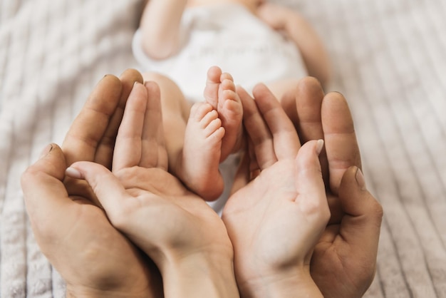 Pernas do bebê nas mãos da mãe e do pai