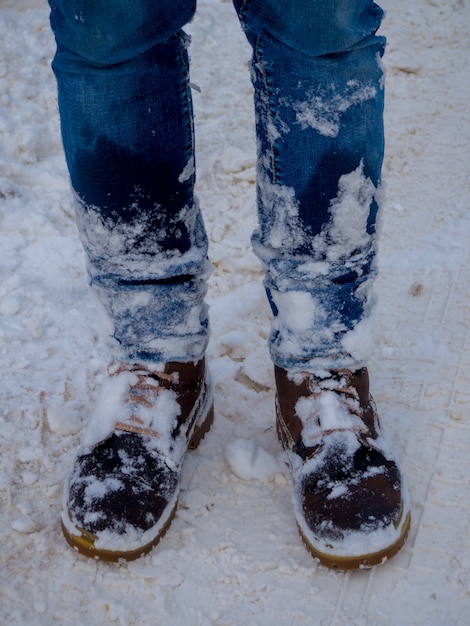Pernas do homem com botas marrons ficam na neve