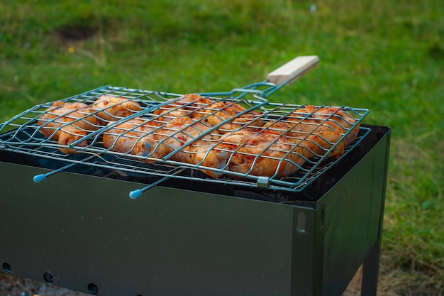 Pernas e asas de frango são fritas em carvões em um braseiro em uma churrasqueira frango marinado é frito em um piquenique