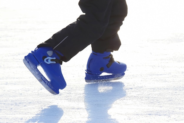 Foto pernas em azul patinando na pista de gelo