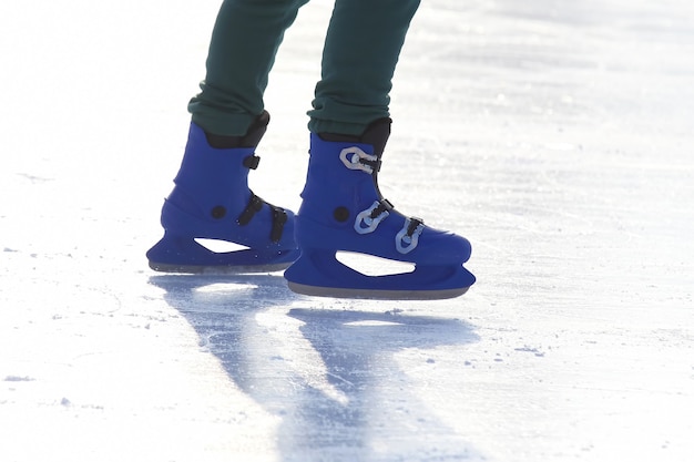 Pernas em azul patinando na pista de gelo