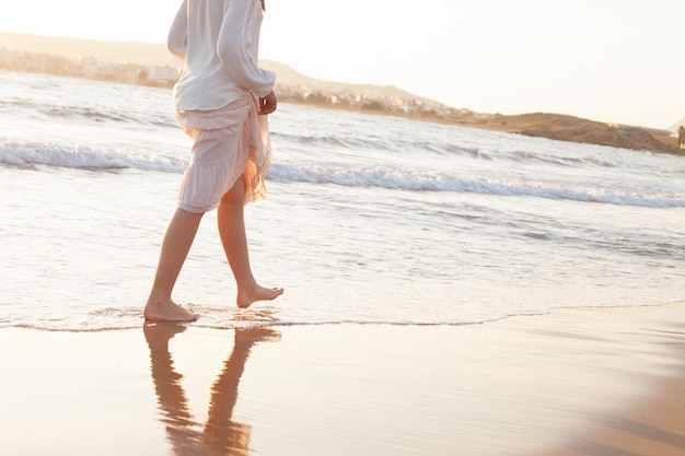 Pernas femininas andando nas férias de praia. Descalço e água do oceano em viagens de férias de verão
