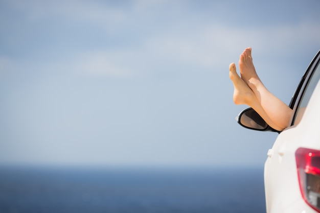 Pernas femininas contra o azul do mar e do céu Conceito de férias de verão