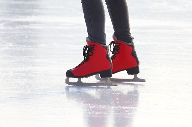 Pernas femininas de patins em uma pista de gelo