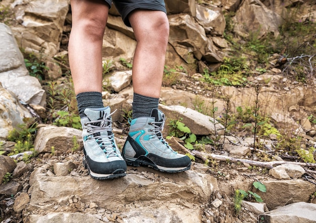 Pernas femininas em botas de caminhada na rocha