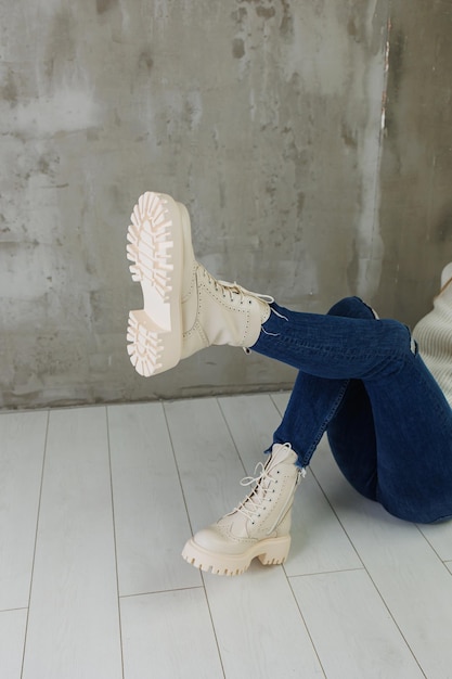 Pernas femininas em jeans e botas de couro branco feitas de couro natural Uma coleção de sapatos femininos modernos de primavera