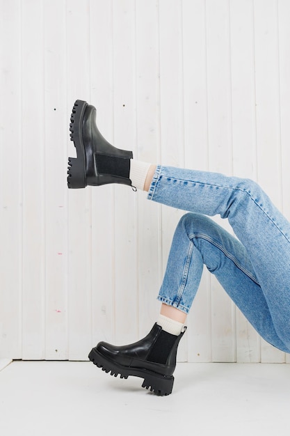 Pernas femininas em jeans e botas de couro preto Sapatos femininos de inverno
