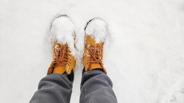 Pernas femininas femininas em rastreamento de sapatos botas tênis no fundo da superfície branca de neve gelada