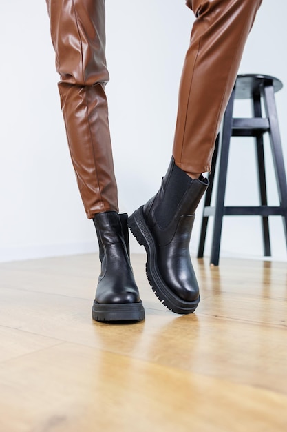 Pernas femininas finas em botas chelsea de couro preto Botas femininas springautumn Pernas femininas em calças marrons de couro